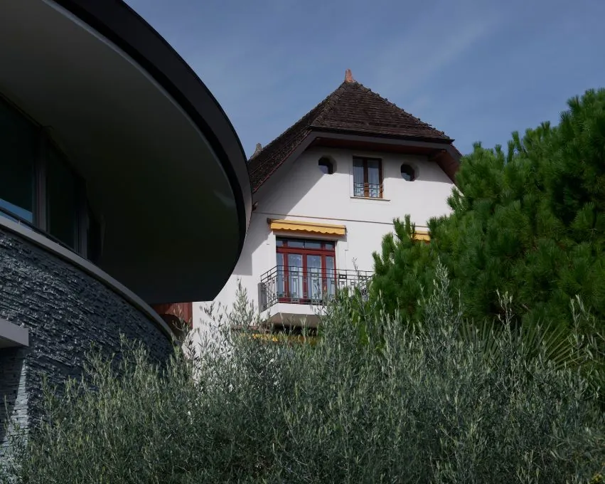 Clinique La Prairie in Montreux: a historic villa next to a curved modern wing, framed by olive trees and pines